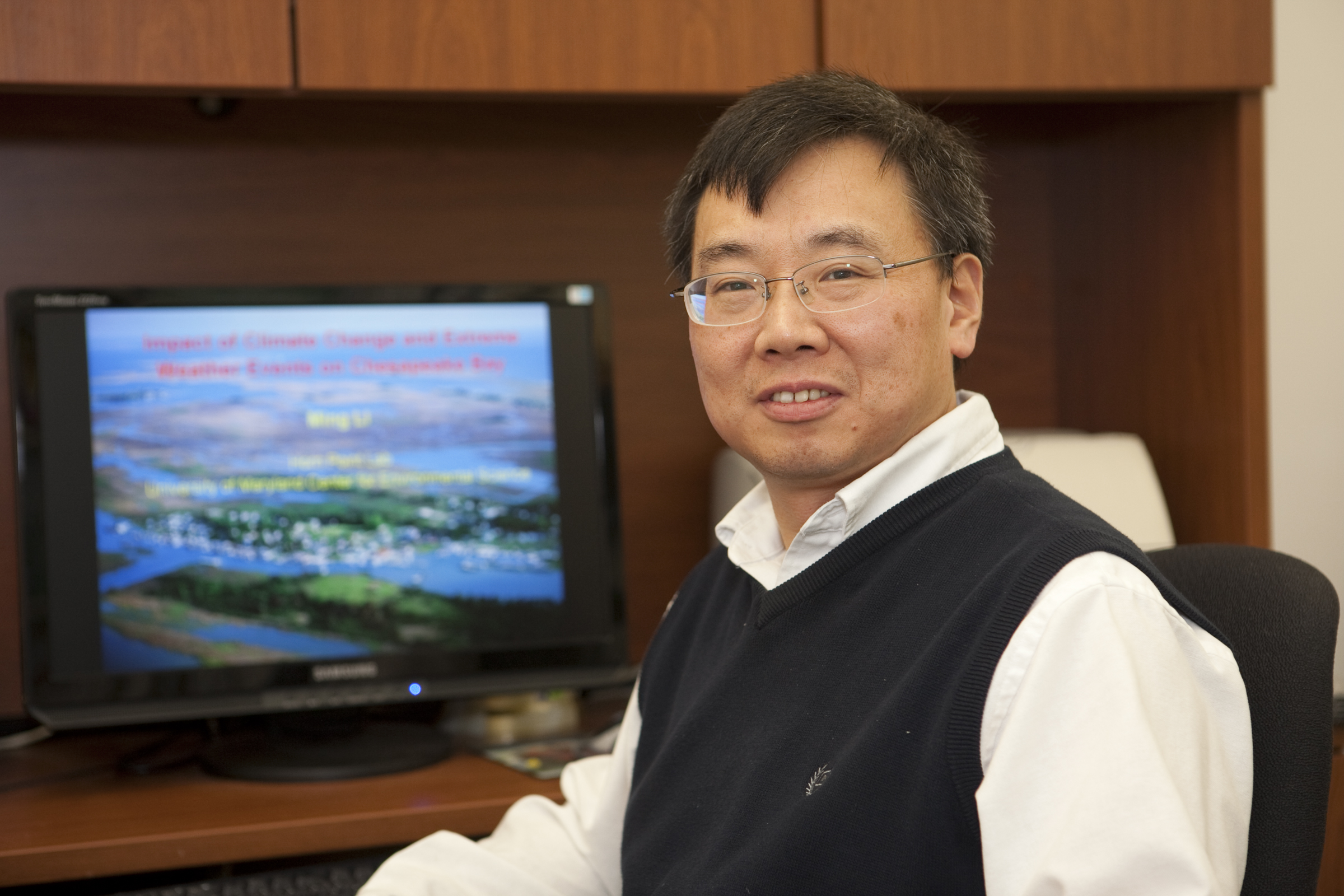 Ming Li sits at his desk in his office.