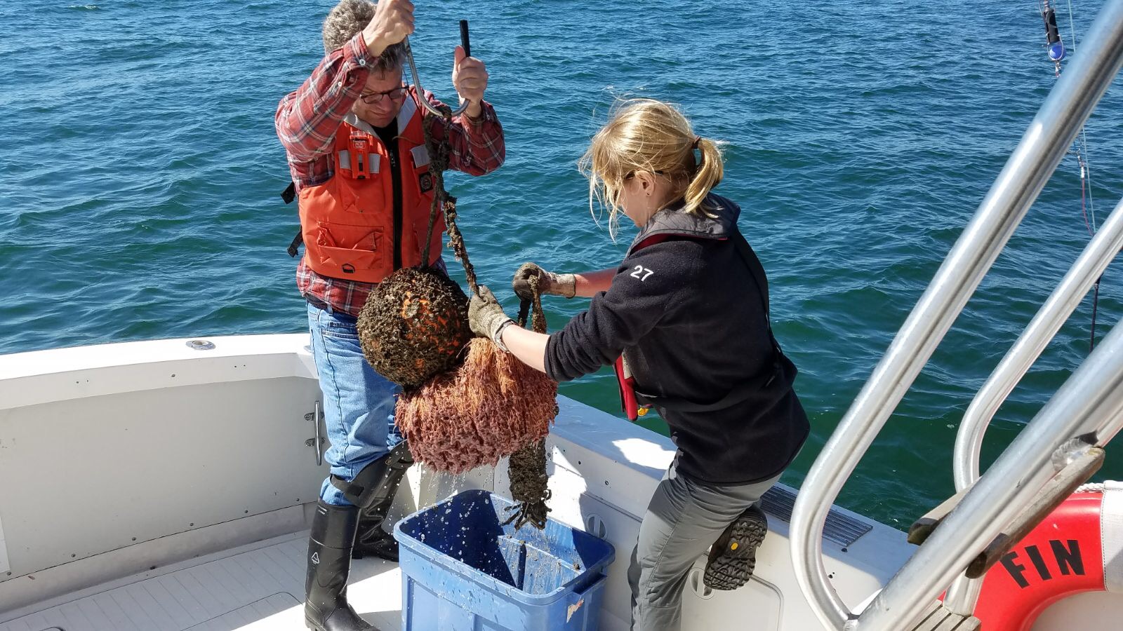 Ellie Rothermel and Dave Secor tending an acoustic receiver. In order to maintain the receiver, researchers bring it on board to clean it and download detection data..